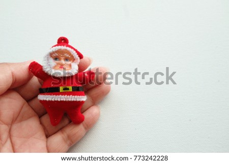 A Santa Claus doll on woman hand and white background.