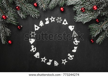 Upper, top, view from above, of handmade wooden toys circle, round shape, evergreen branches on black background, with space for text writing, greeting.