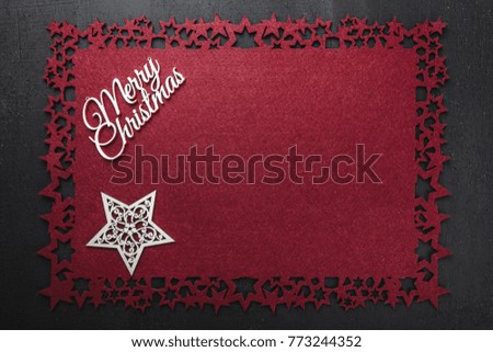 Merry Christmas inscription on red cloth background and wooden handmade star, view from above with free space for text writing. 