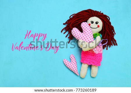 Knitted doll with pink heart on blue background