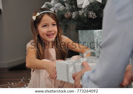 Smiling girl taking gift from mom hands. Giving present to a happy child