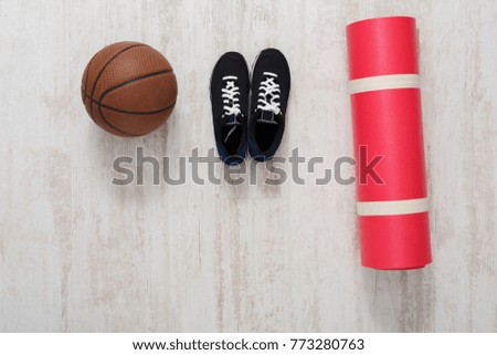 Sports equipment on parquet floor top view. Basket ball, yoga mat and sneakers. Active lifestyle, body care concept
