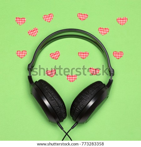 Music for enamored concept. Headphones with small textile hearts on green background. Romantic songs about love