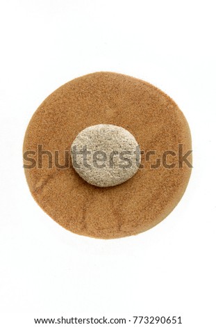 Stone pebble placed on a fine desert sand arranged in a circular shape. A graphic composition of an abstract nature elements.