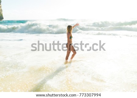 Catch a wave. Full length of a nice young woman standing on the beach while enjoying the view