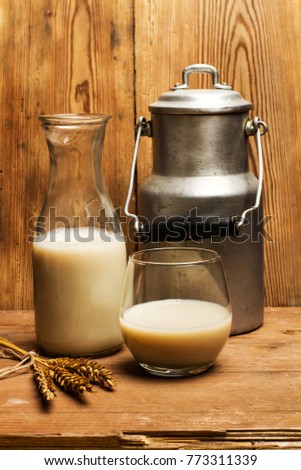Vintage dairy can, a glass and a bottle of milk on a wooden background