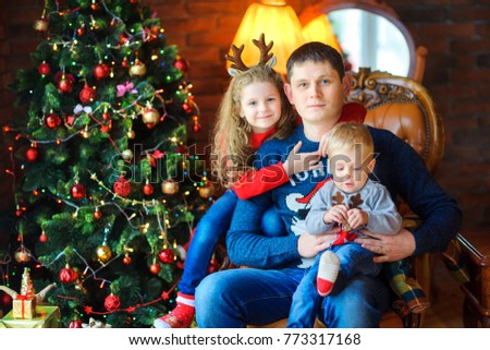 dad with loved ones to sit in a chair near the festive tree, gently embrace and smile
