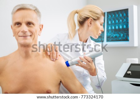 Professional diagnostician. Serious smart nice woman holding a diagnostic device and looking at the monitor while checking her patients health