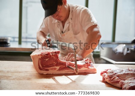 Young butcher sawing meat for sale at a butcher's shop