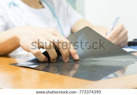 Men dressed in white holding a film x ray while writing treatment plan for patients at the room of the hospital.