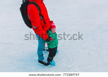 father and little daughter learning to skate in winter