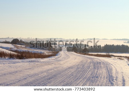 Automobile snow-covered road among the fields. Russia, December, 2017.