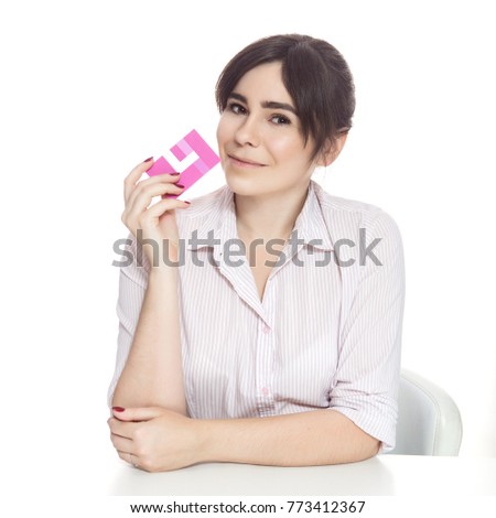 Brunette caucasian woman using her card for work, sitting in front of a desk. She smiles cheerfully