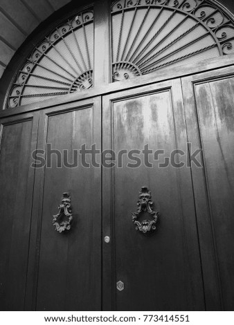 Elegant italian ancient door with doorknockers. Black and white photo.