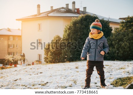 Outdoor portrait of young 6 year old boy wearing warm jacket and boots, enjoying winter time