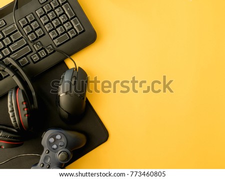 gamer workspace concept, top view a gaming gear, mouse, keyboard, joystick, headset, on yellow table background with copy space