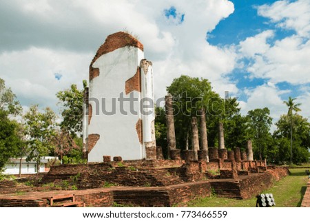 Behind the Buddha Image and Ruins,There are trees and the sky is the background. 