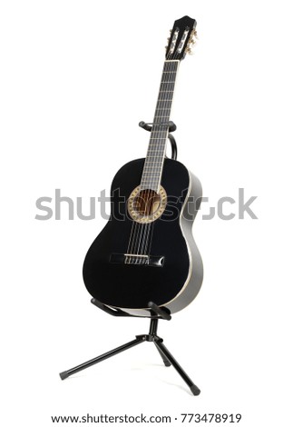 Black classical guitar with on a guitar stand isolated on white background.