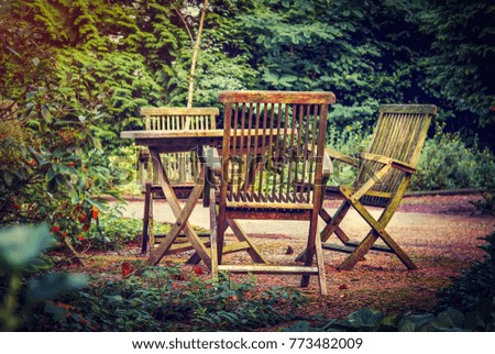 Old wooden table and chairs in the green garden of country house. Holidays in countryside in fresh air