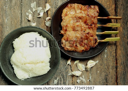 In this picture, there is sticky rice, grilled pork. Garlic is a component.