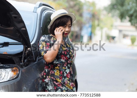 Asian women using smartphone to call the insurance company to see the car parked waiting to repair the side.