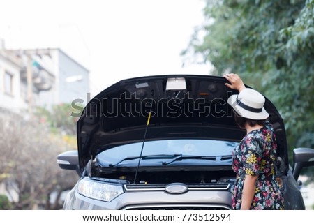 Asian women wait for insurance company to see the car parked waiting to repair the side.