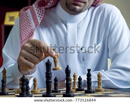 A headless shot of an Arab man playing chess at his desk, wearing Saudi Arabian thob #2 Royalty-Free Stock Photo #773526844