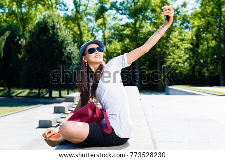 Young Asian woman making selfie pictures outdoors in the park in a sunny day