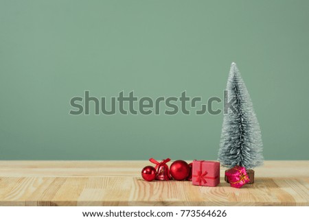 Christmas background. Little Christmas tree with decorations on a light wooden table. Green background. Space for text. New Year's background.