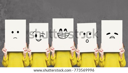 Emotions set. Girl hiding face behind signboard with drawn smileys. Collage of indifferent, winking, happy, surprised, and sad emoticons. Royalty-Free Stock Photo #773569996