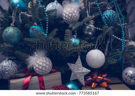 Elegant decorations in white and blue colors hanging on a Christmas tree. A pile of beautiful gift boxes tied with red metallic ribbons. Close up. Christmas or New Year banner.