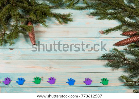 Christmas background with spruce branches with colored traces of palms on wooden board with copy space. 