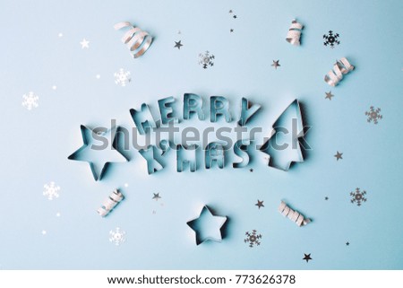 Merry Christmas text with sparkles and shapes for gingerbread on blue pastel background. Flat lay style. Concept of celebrating new year. Christmas mood.