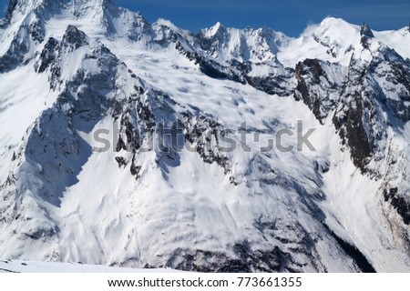 Snow covered mountains with glacier at cold sun day. Caucasus Mountains, region Dombay in winter.