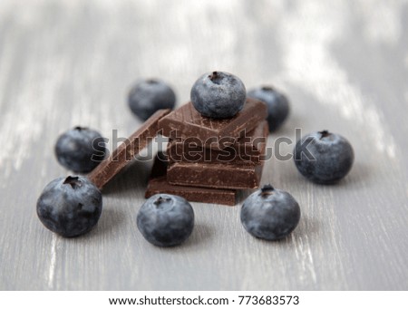 Closeup Dark Chocolate Stack and Fresh Organic Blueberries on Wooden Background Natural Light Selective Focus