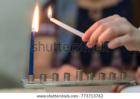 Children's hand lights Chanukah candles