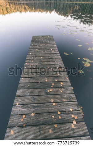 lake with water reflections in colorful autumn day with white clouds in blue sky with old wooden boardwalk- vintage effect