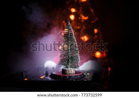Dj mixer with headphones on dark nightclub background with Christmas tree New Year Eve. Close up view of New Year elements or symbols (Santa Clause, Snowman, Dog 2018, gift box) on a Dj table.