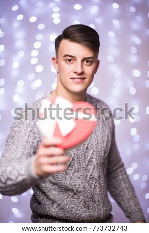 Portrait of Smiling man with Christmas gift on bokeh background. Man with gift on blur light