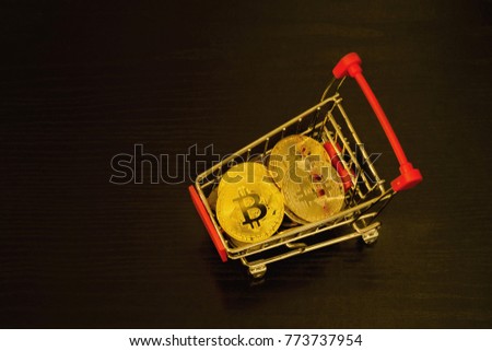 Bitcoin coins in shopping cart. Black background