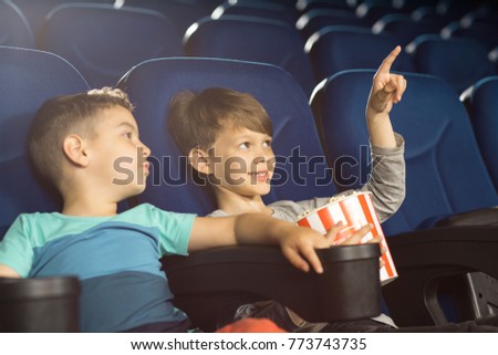 Shot of a cute little boy pointing at the screen at the cinema showing something to his little friends. Young boys enjoying a movie together children childhood family leisure weekend entertaining holi