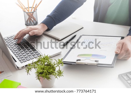 Businessman holding a pen is working with graph documents and sunset light background. Stock market chart and finger pointing on tablet in office.