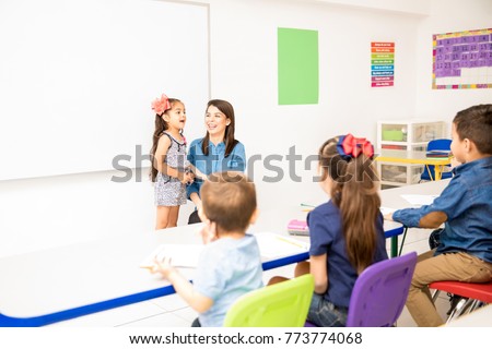 Beautiful little girl participating in class and reciting a poem in a preschool classroom Royalty-Free Stock Photo #773774068