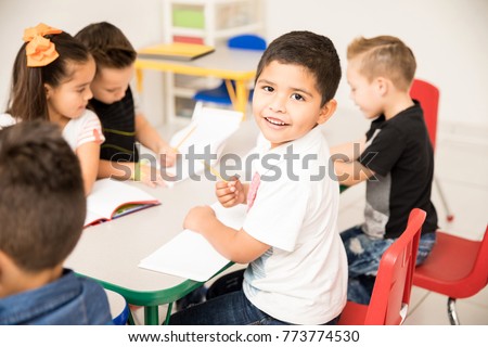 Portrait of a Latin preschool pupil working on a writing assigment and enjoying school Royalty-Free Stock Photo #773774530
