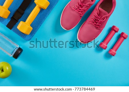 Athlete's set with female clothing, dumbbells and bottle of water on bright blue background Royalty-Free Stock Photo #773784469
