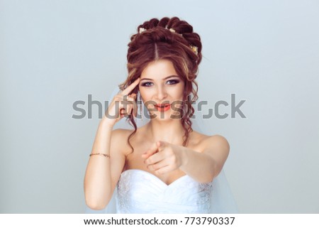 You crazy. Portrait smiling girl bride showing finger at you camera, showing hand gesture this is you with one hand and you are crazy with other, isolated light blue wall background with copy space