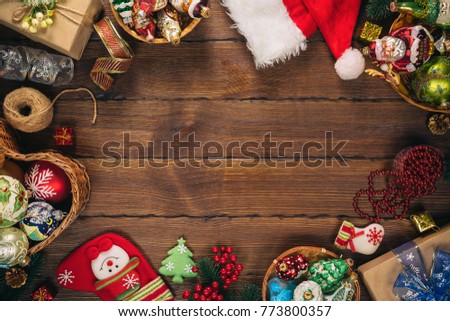 Christmas background with gifts, toys, tree branches, New Year decor, candies, and gingerbread cookies on old wooden background. Frame with free space. Merry Christmas greeting card