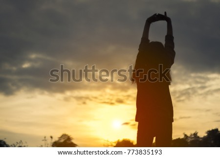Silhouette of young woman relaxing in summer sunset sky outdoor. People freedom style.