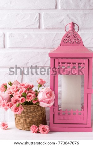 Pink roses flowers and decorative pink  lantern against  white brick wall. Floral still life.  Selective focus. Place for text. Vertical image.
