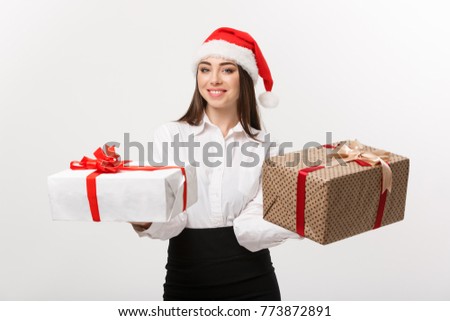 Christmas Concept - young happy caucasian business woman with santa hat giving a choice of gift boxs to camera with copy space on side.